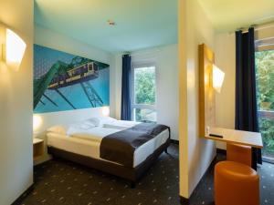 a hotel room with a bed and a train painting on the wall at B&B HOTEL Wuppertal City-Süd in Wuppertal