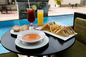 a table with a sandwich and french fries and a drink at Protea Hotel by Marriott Benin City Select Emotan in Benin City
