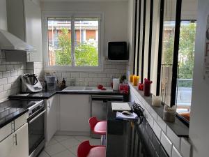 een witte keuken met rode krukken bij Appartement 65m2 avec balcon in Neuilly-sur-Seine