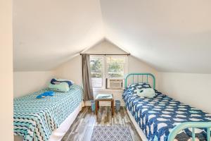 two beds in a attic room with a window at Beachy Outer Banks Retreat with Deck and Grill! in Kill Devil Hills
