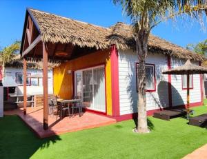 una pequeña casa con techo de paja y patio verde en La Marina Resort, en La Marina
