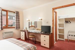 Habitación de hotel con escritorio y cama en Highlander Hotel ‘A Bespoke Hotel’, en Newtonmore