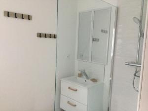 Baño blanco con lavabo y espejo en gites de terophey & kena, en Thiberville