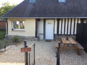 een huis met een witte deur en een houten tafel bij gites de terophey & kena in Thiberville