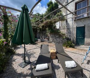 een groene paraplu en twee stoelen en een tafel en een bank bij Casa Armeno a Ravello in Ravello