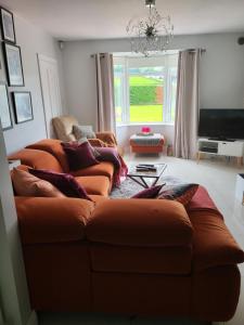 Sala de estar con 2 sofás marrones y TV en Tullyvinney Lodge, en Raphoe