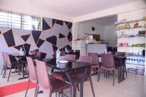 a dining room with tables and chairs and a kitchen at Grand Misty Heaven in Madikeri