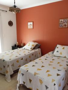 two beds in a room with orange walls at Chez Mamiyo in Gallargues-Le-Montueux