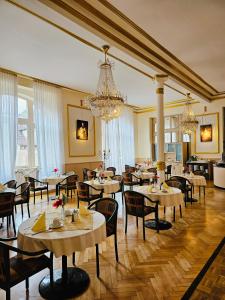 a restaurant with tables and chairs and a chandelier at Gala Hotel in Pforzheim