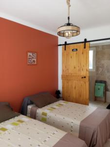 a bedroom with two beds and a wooden door at Chez Mamiyo in Gallargues-Le-Montueux