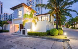 una casa blanca con palmeras y una calle en HOLLYWOOD Luxury PoolVilla Pattaya walking street 4 Bedrooms, en Pattaya South