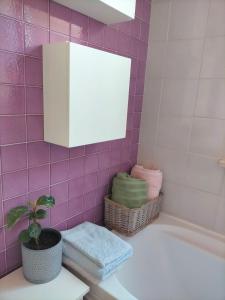 een roze betegelde badkamer met een bad en een plant bij Appartamento Chiara - Pescara in Pescara