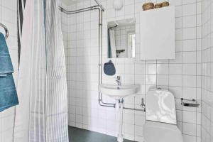a white bathroom with a sink and a mirror at Bright apartment in park environment in Lund