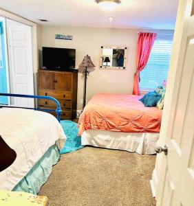 a bedroom with two beds and a flat screen tv at Mini Pearl, Private 2 BR - 1 block to BEACH! in Tybee Island