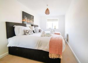 a bedroom with a large bed with white sheets and an orange blanket at 2 Bed Charming Corner Position Apartment in Kidlington