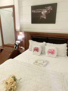 a bed with white sheets and pink flowers on it at GRAD Dai Thanh Hotel in Hanoi