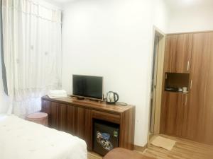 - une chambre avec un lit et une télévision sur une armoire en bois dans l'établissement GRAD Dai Thanh Hotel, à Hanoï