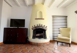 a living room with a fireplace with a tv and a chair at Balcones Del Mar in Rosarito