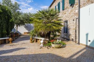 a patio with a bench and a palm tree and flowers at B&B Corte dei Ducati in Comacchio