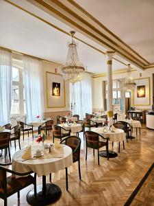 a restaurant with tables and chairs and a chandelier at Gala Hotel in Pforzheim