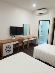 1 dormitorio con 2 camas y escritorio con TV en GRAD Korea Hotel 2, en Làng Thành