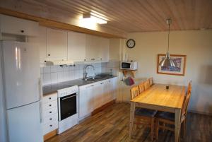 a kitchen with a wooden table and a white refrigerator at Idre Fjäll, Söderbyn Ski in Ski out, 30 m till pisten in Idrefjäll