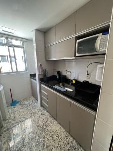 eine kleine Küche mit einer Spüle und einer Mikrowelle in der Unterkunft Locking's Savassi 10 in Belo Horizonte