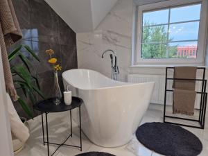 a white bath tub in a bathroom with a window at Seliu 25 Homestay Apartment poilsio namai in Šiauliai
