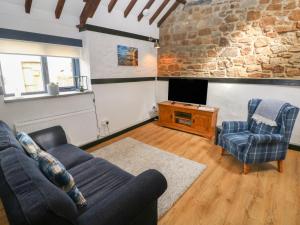 a living room with a couch and two chairs and a tv at Honeysuckle Cottage in Narberth