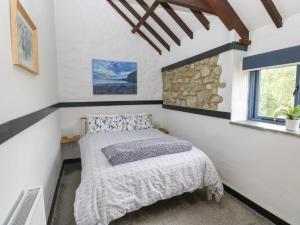 a bedroom with a bed and a stone wall at Honeysuckle Cottage in Narberth