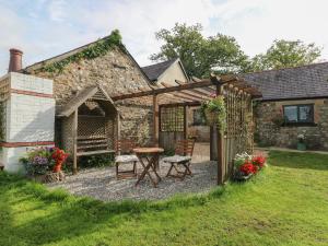 a patio with a table and chairs in front of a building at Honeysuckle Cottage in Narberth