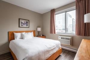 - une chambre avec un grand lit et une fenêtre dans l'établissement Hotel le Roberval, à Montréal