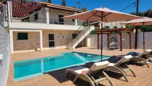 een zwembad met stoelen en een parasol en een huis bij Angelo’s villa in Avliótai