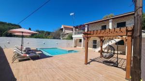 a wooden deck with a swing and a swimming pool at Angelo’s villa in Avliótai
