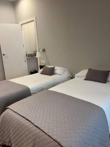 two beds in a hotel room with a mirror at Precioso y céntrico apartamento in Zaragoza