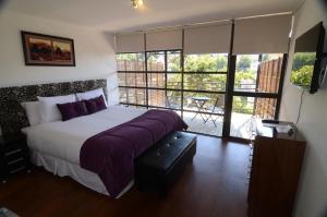 a bedroom with a large bed and a balcony at Hotel Cabernet in Valparaíso