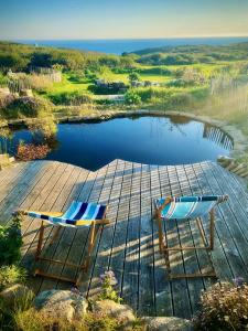 dos sillas sentadas en un muelle junto a un lago en Bohémienne regarde la mer. en Plogoff