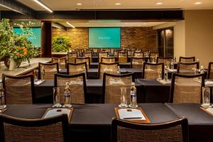 a conference room with tables and chairs and a screen at Hotel Fasano Rio de Janeiro in Rio de Janeiro