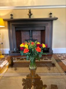 a vase of flowers on a table in front of a fireplace at Moresby Hall Country House Hotel in Whitehaven