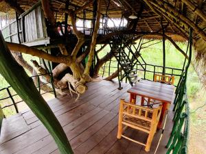 una terraza de madera con una mesa y un árbol en Yala Beddegama Eco en Kataragama