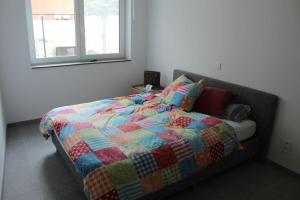 a bedroom with a bed with a colorful quilt at Ruim nieuwbouwappartement oostduinkerke in Oostduinkerke