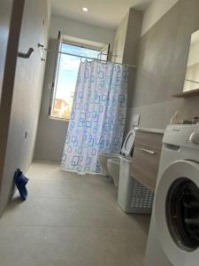 a bathroom with a washing machine and a shower curtain at Lukas Apartament Vollga Durres in Durrës