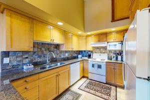 a kitchen with wooden cabinets and a white refrigerator at Tree Tops 12 - Suite in Big White