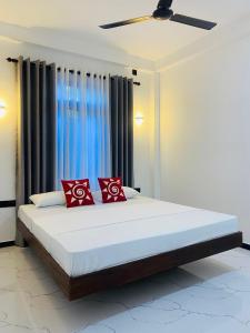 a bedroom with a large bed with red pillows at Thanu Villa in Unawatuna