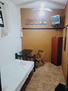Pousada das Artes 2 في مونغاغوا: غرفة بها سرير وتلفزيون على الحائط