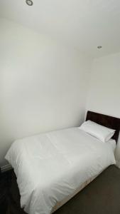 Cama blanca con sábanas y almohadas blancas en Roomy 2 bed flat in London en Thornton Heath