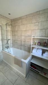 a bathroom with a tub with a shower and towels at Roomy 2 bed flat in London in Thornton Heath