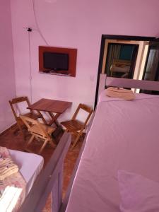 um quarto com duas camas e uma mesa e uma televisão em Pousada das Artes 2 em Mongaguá
