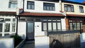 a white house with a black door and a fence at Roomy 2 bed flat in London in Thornton Heath