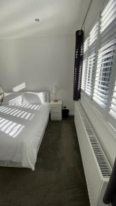 a white bedroom with a bed and a window at Roomy 2 bed flat in London in Thornton Heath